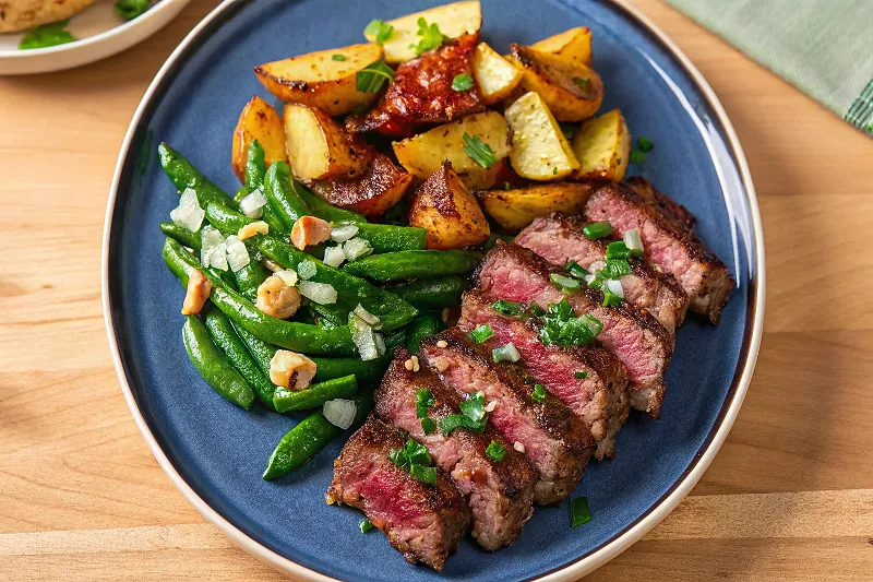 Perfectly seared Seared Steak and Bacon Roasted Potatoes with Nutty Green Beans and Garlic-Parsley Butter served professional style